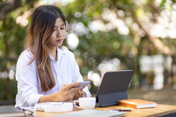 Outdoor business woman wearing casual clothes is working on a laptop and modern equipment in a natural and comfortable setting.