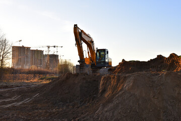 Excavator on earthmoving on sunset. Loader on excavation. Excavator digs gravel. Earth-Moving Heavy...