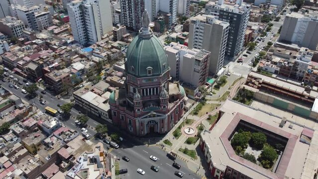 Drone 4k video of a church in Lima, Peru. In the district of "Magdalena del mar" Drone orbits around the dome with statue of virgin mary and camera tilts up showing many buildings and ocean in horizon
