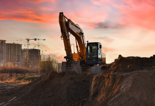 Excavator on earthmoving on sunset. Loader on excavation. Excavator digs gravel. Earth-Moving Heavy Equipment for Construction. Earth mover ar construction site. Backhoe Loader. Road construction.