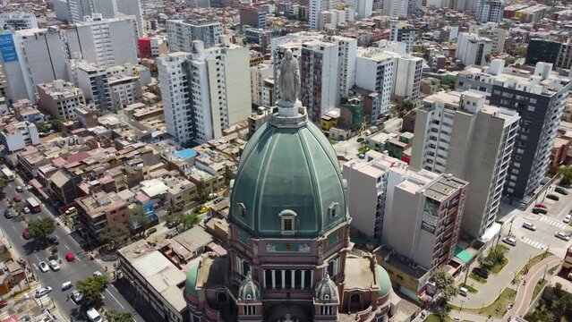 Drone 4k video of a church in Lima, Peru. Drone starts from the statue of the virgin mary and flies back and up revealing the dome of the tall church standing above all other buildings in background.