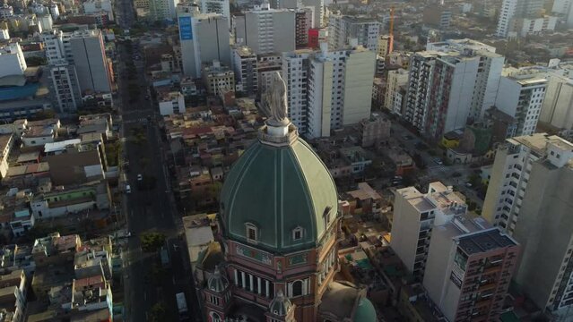 Drone video of the tallest church in Lima, Peru. It's called "iglesia del Inmaculado Coraz&oacute;n de Mar&iacute;a" Drone orbits while slowly tilting camera up. Many small and tall buildings in background.