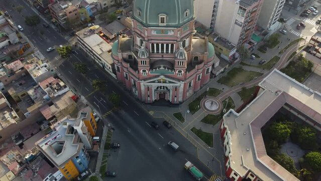 Drone 4k video of a church in Lima, Peru. Drone hovers at high altitude and tilts up revealing the church's dome and the statue of the virgin mary on top. Many buildings behind and around it.