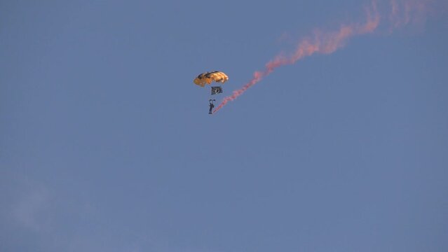 parachuters with smoke trail landing 