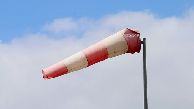 Red and white windsock on a windy day.