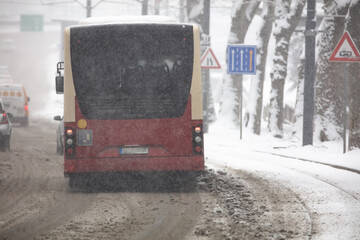 Bus public transportation driving on snowy streets in winter conditions.