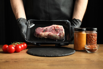 The chef is holding a beef steak in a store's plastic packaging.