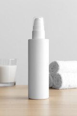 White cosmetic lotion bottle mockup with a candle and towels on the wooden table.