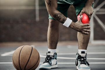 Sports, injury in basketball and knee pain or athlete man while on an outdoors court holding his...
