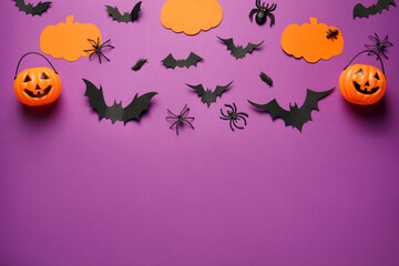 Flat lay composition with pumpkins, spiders and paper bats on purple background, space for text. Halloween celebration