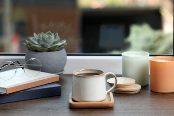 Cup of coffee with books and home decor on wooden window sill