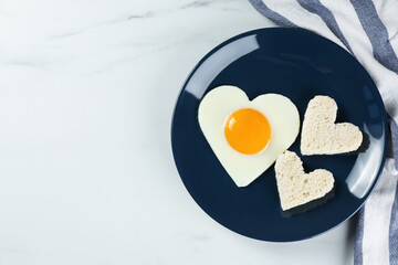 Romantic breakfast with heart shaped fried egg and toasts on white marble table, flat lay. Space for text