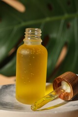 Obraz na płótnie Canvas Bottle of face serum on soap dish against beige background, closeup
