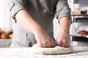 Obraz na płótnie Canvas Man kneading dough at table in kitchen, closeup