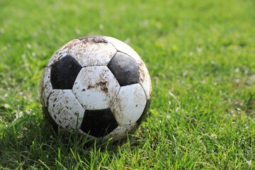 Fototapeta premium Dirty soccer ball on green grass outdoors, space for text