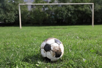 Dirty soccer ball on green grass outdoors, space for text