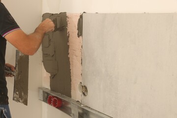 Worker installing tile in room, closeup. Home improvement