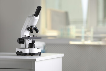 Modern medical microscope on lab drawer indoors, space for text. Laboratory equipment