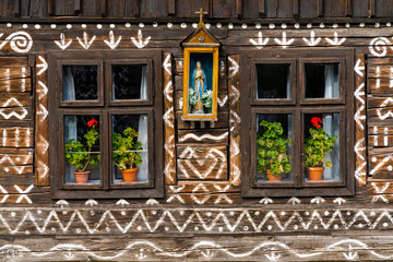 close-up view of a house front with typical white paint patterns and a saint figure in the village center of Cicimany in Slovakia