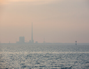 Obraz premium Blick vom Friesenstrand in Tossens über den Jadebusen auf die Industrieanlagen in Wilhelmshafen bei Sonnenuntergang