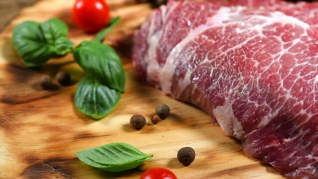Raw meat. Prime fillet meat. Marble beef steak, Black Angus Steak Rib eye. Spices. On wooden plate. Slow motion 