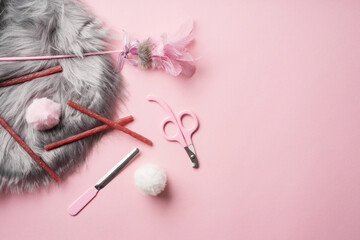 Flat lay with cat accessories. A set for trimming pet claws: a file and a nail cutter, feathers toy, cat snacks, fur pom-poms and a gray mat. Pink cat nail clipper.