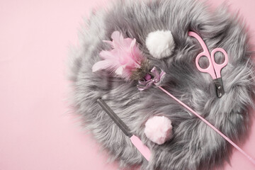 A set for trimming pet claws: a file and a nail cutter, feathers toy, fur pom-poms on a gray mat. Pink cat nail clipper.