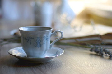 Cup of tea, plate with chocolate chip cookies, open book, reading glasses, lit candles and dry lavender flowers. Hygge at home, selective focus.