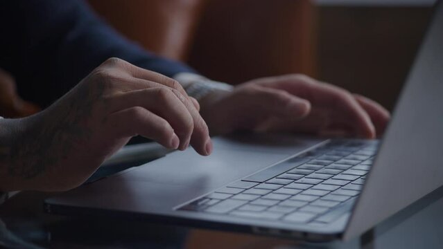 Tattooed hands scroll and swipe on laptop touchpad shot handheld close up pivoting around