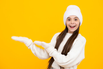 Teenager child pointing to the side with a finger to present a product or idea. Teen girl in casual outfit pointing empty space.