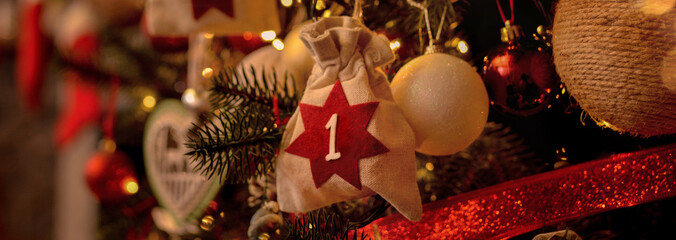 Advent calendar in the form of an eco bag hangs on the Christmas tree against the background of the Christmas room with a fireplace and Santa's boots.Christmas background. Advent calendar.