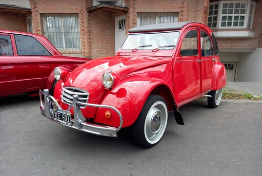 old red popular Citroen 3CV 1960-1979 four door sedan parked on the street. Classic car show.