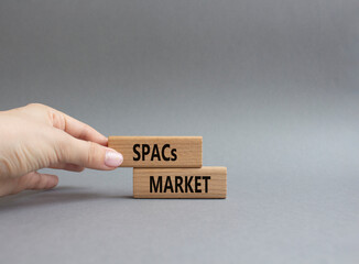 SPACs market symbol. Concept words SPACs market - special purpose acquisition companies market - on wooden blocks. Beautiful grey background. Businessman hand. Business concept. Copy space.