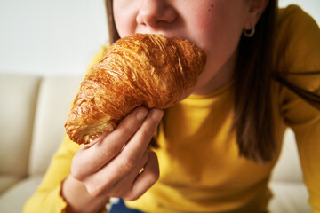 Girl in yellow top holding a fresh croissant