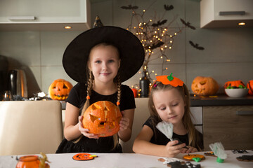 children in masquerade costumes  paint gingerbread for the halloween holiday at home in the kitchen
