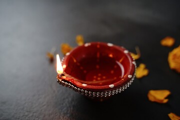 Happy Diwali background - Colorful Clay Diya lit during Deepavali festival on black background, top down view