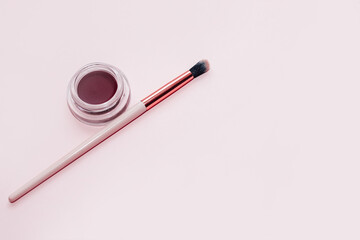 A jar with eyeshadow and eyebrow pomade on a white background.