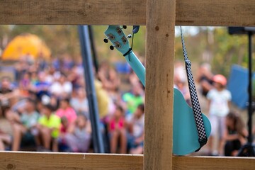 Closeup shot of a blue ukulele with an audience in the background