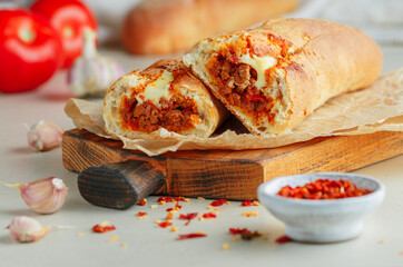 Baguette stuffed with bolognese ragout of minced beef, tomatoes, onions, spices and cheese. A delicious Italian lunch, homemade sandwich close-up. A Mediterranean dish. Selective focus