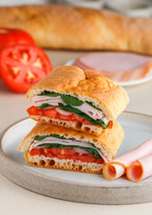 Baguette stuffed with tomatoes, onions, ham, spinach, basil. A multi-layered snack for gourmets. Healthy breakfast. Mediterranean cuisine. Selective focus