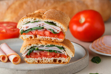 Baguette stuffed with tomatoes, onions, ham, spinach, basil. A multi-layered snack for gourmets. Healthy breakfast. Mediterranean cuisine. Selective focus