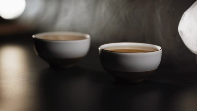 Two bowls with Japanese tea on a black background. The concept of a tea ceremony