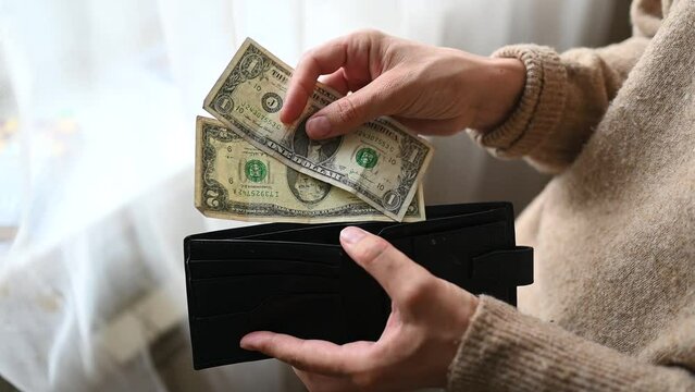 A woman's hand takes money out of her purse