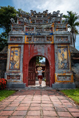 Fototapeta premium Mujer turista con sombrero vietnamita paseando por los interiores de la antigua capital imperial de Hue, en Vietnam