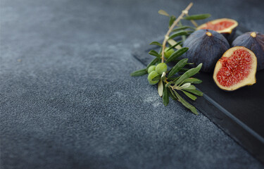 fresh ripe figs fruit and olive branch on dark table. mediterranean food concept