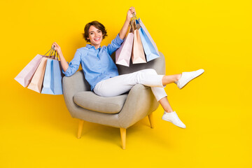 Full length photo of pretty positive girl dressed blue shirt rising bargains empty space isolated yellow color background