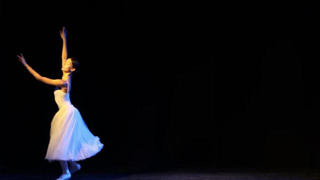 Grand Jete en Tournant. Graceful ballerina in elegant white dress jumping, dancing over dark background. Concept of beauty, tenderness, achievement, skills
