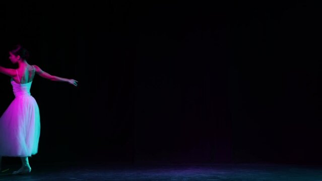 Solo. Beautiful and graceful ballet dancer dancing on dark theater stage in neon light. Art, fantasy, flexibility, inspiration concept.