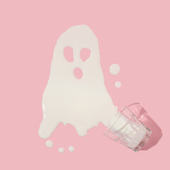 Halloween creative layout with  glass of spilled milk forming ghost on pastel pink background. 80s,...