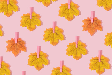 Autumn creative pattern made with leaves with pink clothes hanging clips on pastel pink background. Vintage retro aesthetic 80s or 90s fashion concept. Minimal autumn season idea.